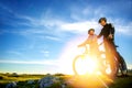 Cyclist couple with mountain bikes standing on the hill under the evening sky and enjoying bright sun at the sunset. Royalty Free Stock Photo