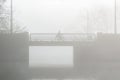 A cyclist crossing a bridge on a misty day