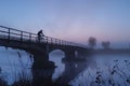 cyclist crossing misty bridge at dawn
