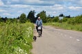 Cyclist and dog outdoors in the countryside. A male farmer rides a bicycle along a village street, followed by a pet. Editorial