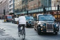 Cyclist going past taxis waiting to turn on Oxford Street, London, UK.