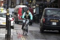 A cyclist in a gray-green jacket and with a bag