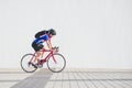 Cyclist in a helmet, athletic cycling clothes and a backpack rides on the background of a white wall Royalty Free Stock Photo