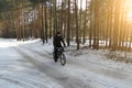 Cyclist without a helmet rides on snow-covered forest road on Bicycle on Sunny spring day Royalty Free Stock Photo