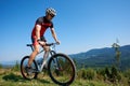 Cyclist in helmet, sunglasses and full equipment riding bike on grassy hill Royalty Free Stock Photo