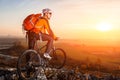 Cyclist with mountain bike on top observing the view. At sunset with lens flare Royalty Free Stock Photo