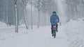 The cyclist moving on the street during the snow blizzard.