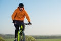 A cyclist in an orange hoodie rides a bike along a mountain path. The concept of extreme sports.