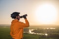 Cyclist at sunset in the mountains. A young man in a helmet and glasses drinks water from a bottle.