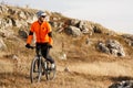 Cyclist in Orange Jacket Riding the Bike on the Rocky Trail. Extreme Sport Concept. Space for Text. Royalty Free Stock Photo