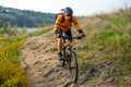 Cyclist in Orange Riding the Mountain Bike on the Autumn Rocky Trail. Extreme Sport and Enduro Biking Concept. Royalty Free Stock Photo