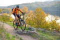 Cyclist in Orange Riding the Mountain Bike on the Autumn Rocky Trail. Extreme Sport and Enduro Biking Concept. Royalty Free Stock Photo