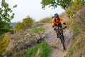 Cyclist in Orange Riding the Mountain Bike on the Autumn Rocky Trail. Extreme Sport and Enduro Biking Concept. Royalty Free Stock Photo