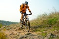 Cyclist in Orange Riding the Mountain Bike on the Autumn Rocky Trail. Extreme Sport and Enduro Biking Concept. Royalty Free Stock Photo