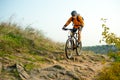 Cyclist in Orange Riding the Mountain Bike on the Autumn Rocky Trail. Extreme Sport and Enduro Biking Concept. Royalty Free Stock Photo