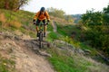 Cyclist in Orange Riding the Mountain Bike on the Autumn Rocky Trail. Extreme Sport and Enduro Biking Concept. Royalty Free Stock Photo