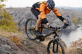 Cyclist in Orange Wear Riding the Bike Down Rocky Hill under River