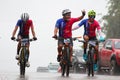 Cyclist reach the mountain while its raining but have a happy reaction of the event