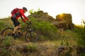 Cyclist in Red Jacket Riding Mountain Bike on Beautiful Spring Rocky Trail at Sunset. Adventure and Extreme Sport Concept Royalty Free Stock Photo