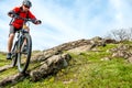 Cyclist in Red Jacket Riding Mountain Bike Down Rocky Hill. Extreme Sport and Adventure Concept.