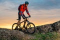 Cyclist in Red Riding the Bike on Autumn Rocky Trail at Sunset. Extreme Sport and Enduro Biking Concept. Royalty Free Stock Photo