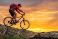 Cyclist in Red Riding the Bike on Autumn Rocky Trail at Sunset. Extreme Sport and Enduro Biking Concept. Royalty Free Stock Photo