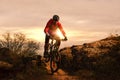 Cyclist in Red Riding Bike on the Autumn Rocky Trail at Sunset. Extreme Sport and Enduro Biking Concept. Royalty Free Stock Photo