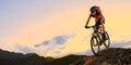 Cyclist in Red Riding the Bike Down the Rock at Sunset. Extreme Sport and Enduro Biking Concept. Royalty Free Stock Photo