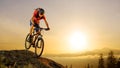 Cyclist in Red Riding the Bike Down the Rock at Sunrise. Extreme Sport and Enduro Biking Concept. Royalty Free Stock Photo