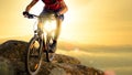 Cyclist in Red Riding the Bike Down the Rock at Sunrise. Extreme Sport and Enduro Biking Concept.