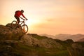 Cyclist in Red Riding Bike on the Summer Rocky Trail at Sunset. Extreme Sport and Enduro Biking Concept. Royalty Free Stock Photo