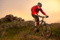 Cyclist in Red Riding Bike on the Spring Rocky Trail at Sunset. Extreme Sport and Enduro Biking Concept. Royalty Free Stock Photo