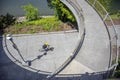 Cyclist rides along a path along a river under an oval bridge