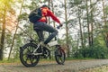Cyclist rides on a bike path in the forest. Riding an electric modern bicycle. Cool fashionable bike with alloy wheels. A cyclist