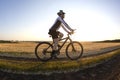 The cyclist rides a bike on the road near the field against the backdrop of the setting sun. Outdoor sports. Healthy lifestyle Royalty Free Stock Photo