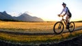 The cyclist rides a bike on the road near the field against the backdrop of the setting sun. Outdoor sports. Healthy lifestyle Royalty Free Stock Photo