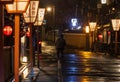 Cyclist rides on dark empty street after rain in historic Japanese district