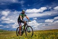 A cyclist rides in the mountains among flowering fields Royalty Free Stock Photo