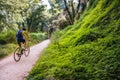 A cyclist rides a path through bushes and tall trees as a healthy activity on the weekend