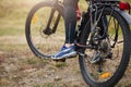 Cyclist rides on road in forest or meadow, Back of road racing cyclist. Faceless picture of man legs, guy stops his bicycle, Royalty Free Stock Photo