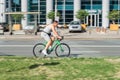 Cyclist riding a bicycle on the city street. Amateur cyclist in gray cycling garment rushing bicycle outdoors on a sunny day