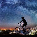 Cyclist riding bike in the night under starry sky Royalty Free Stock Photo