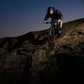 Cyclist Riding the Bike on Rocky Trail at Night. Extreme Sport and Enduro Biking Concept. Royalty Free Stock Photo