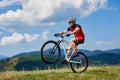 Cyclist riding cross country bike, turning on one wheel of bicycle on mountain hill Royalty Free Stock Photo