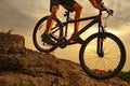 Cyclist Riding the Mountain Bike Down the Rock at Sunset. Extreme Sport and Enduro Biking Concept.