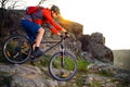 Cyclist Riding Mountain Bike Down Rocky Hill on the Spring Trail at Sunset. Extreme Sports Concept. Royalty Free Stock Photo