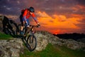 Cyclist Riding Mountain Bike Down Spring Rocky Hill at Beautiful Sunset. Extreme Sports and Adventure Concept. Royalty Free Stock Photo