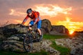 Cyclist Riding Mountain Bike Down Spring Rocky Hill at Beautiful Sunset. Extreme Sports and Adventure Concept. Royalty Free Stock Photo