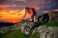 Cyclist Riding Mountain Bike Down Spring Rocky Hill at Beautiful Sunset. Extreme Sports and Adventure Concept.