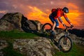 Cyclist Riding Mountain Bike Down Spring Rocky Hill at Beautiful Sunset. Extreme Sports and Adventure Concept.